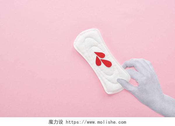 手拿着白色卫生巾在粉红色背景上滴血